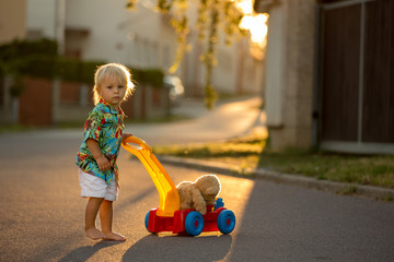 Beautiful toddler child, playing with plastic toys, blocks, cars on sunset
