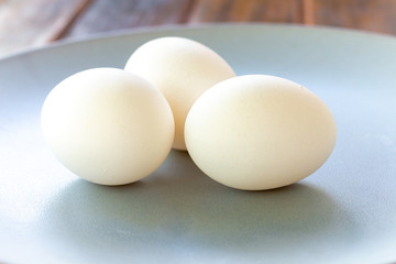 Chicken eggs on a plate and a wooden table.
