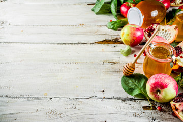 Jewish Autumn Rosh Hashana celebration. Traditional products for the celebration of Rosh Hashanah - apples with leaves, pomegranate, honey, honeycombs, white wooden  background