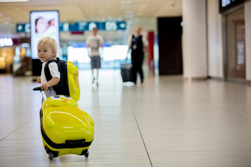 Sweet childre, brothers, boys, waking hand in hand at the airport, carrying suitcases and backpacks