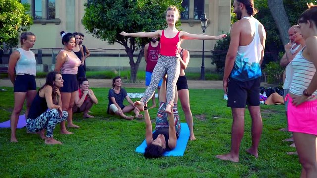 A group lesson on acroyoga master class which takes place on the lawn in the park. Slowmotion shot