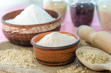 Whole grain rice flour in bowls. White rice red rice black. The whole grain of rice. Unpolished rice in wooden spoon. Healthy food background.