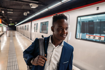 African American businessman wearing blue suit and backpack in metro subway. Business concept