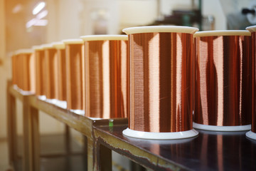 Standard copper wire enamel in a bobbin on the table, steel floor in the factory. The backdrop is a...
