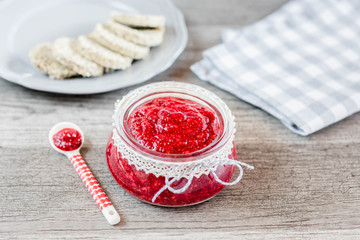 raspberry chia jam in glass jar on wooden background