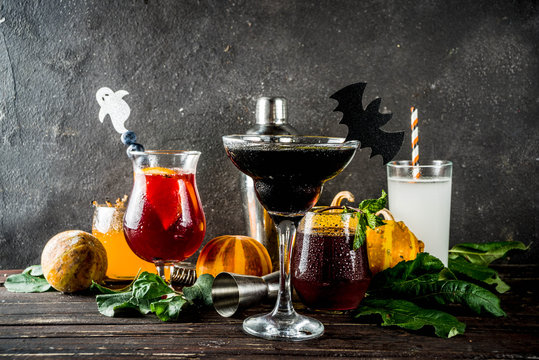 Selection of Halloween traditional autumnal alcoholic cocktails and drinks. Different alcoholic beverages and shots for Halloween party, with autumn decorations, on a wooden table