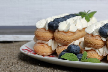Cakes made from Italian savoyardi cookies and cream. Decorated with blueberries and mint leaves. Nearby is a box of white painted wooden boards.