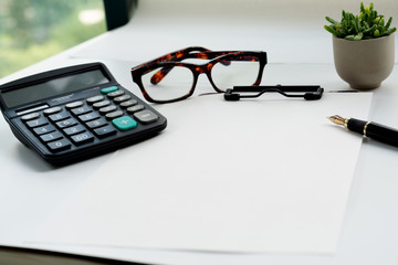 Business objects, clipboard with blank sheet of paper, pen, glasses and calculator on white background