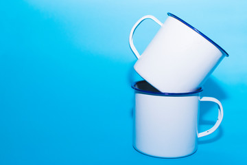 Two white metal cups on a blue background.