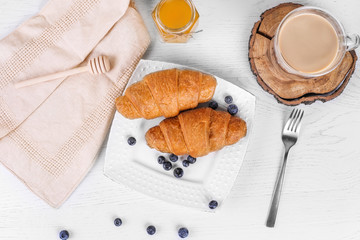 croissants with blueberries on a white plate with coffee and honey. Tasty breakfast. Top view with copy space.