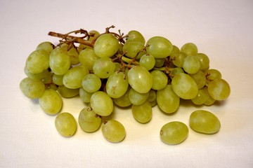 Bunch of green grapes on light fabric background closeup