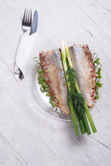 marinated herring fillet on a transporant plate with green onion and seasonings. served in Scandinavian style. Typical cooking fish in Scandinavian countries. copy space