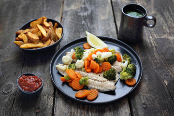 Grilled fish with vegetables, fries and ketchup. Dinner dish. Healthy diet