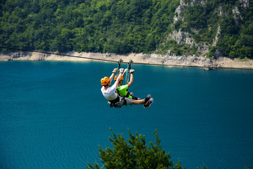 Sliding on a zip line over the blue lake,adrenaline and extreme concept © Novak