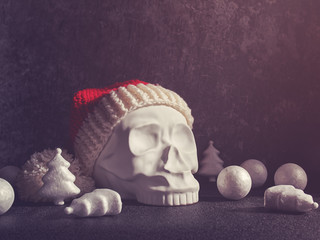 A red Santa Claus hat is put on a decorative sculpture in the form of a human skull. Nearby are...