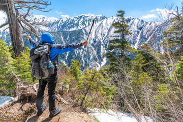 Hiker man hold trekking pole and spreading hand when see snow mountain range at view point.