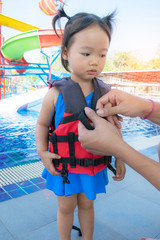 A father helping his daughter with her life jacket.