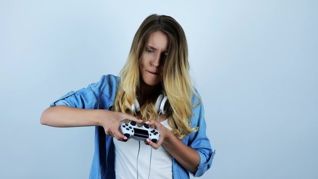 young beautiful sexy blonde woman with headphones on her neck playing video game looking excited on isolated white background