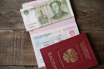 A Russian passport with a Chinese visa and money is one yuan. Visa stamp, passport. Vacation and travel concept. Top view.