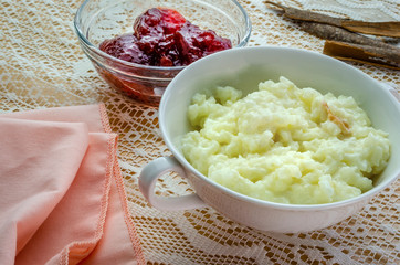 A tasty looking dish of rice pudding with a small bowl of strawberry jam on the side. 