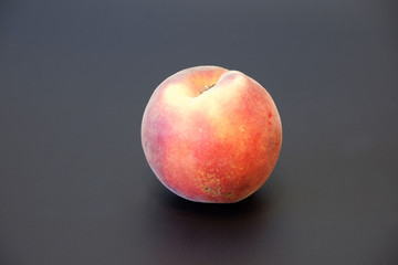 Single fresh juicy orange peach on dark gray background close up
