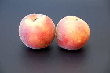 Two fresh juicy peaches on dark gray background close up view