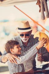 Grandfather and grandson having fun and spending good quality time together in amusement park. Kid...