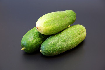 Some fresh organic cucumbers on dark gray matte background close up