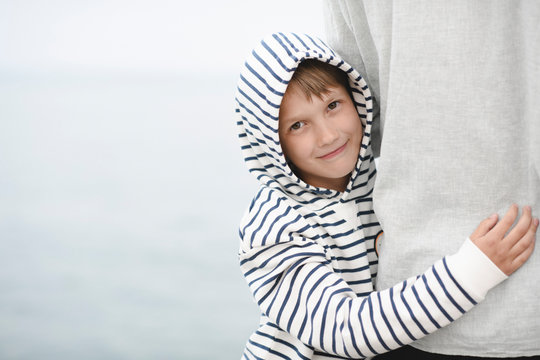Portrait of smiling boy wearing striped hooded jacket hugging his father