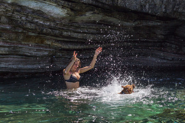 Happy woman having fun with her dog swimming at sea