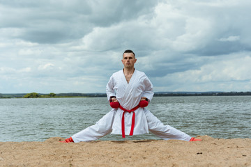 a man in a traditional kimano with a red belt is training a breathing technique. Karate training