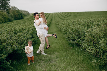 Family with cute little son. Father in a white t-shirt. Lady in a white dress