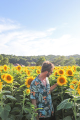 Modelo posando entre campos de girasoles y disfrutando de estas hermosas plantas