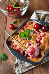 Cherry clafouti in portional ceramic forms on rustic wooden background.