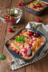 Cherry clafouti in portional ceramic forms on rustic wooden background.
