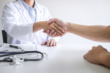 Professional female doctor in white coat shaking hand with patient after successful recommend treatment methods after results about the problem illness, Medicine and health care concept