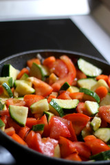 Cooking vegetables in a pan: zucchini, tomato and carrot. Selective focus.