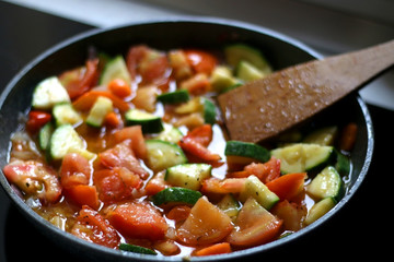 Cooking vegetables in a pan: zucchini, tomato and carrot. Selective focus.
