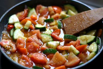 Cooking vegetables in a pan: zucchini, tomato and carrot. Selective focus.