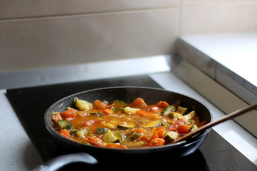 Cooking vegetables in a pan: zucchini, tomato and carrot. Selective focus.