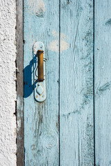 Old door handle and wooden door painted blue. Wooden surface with old blue paint. Old wooden boards.