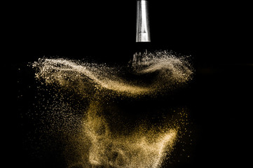 golden powder splash and brush for makeup artist or beauty blogger in black background