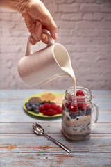glass jug filled with cereals, raspberries and blueberries