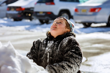 Girl playing with snow and looking up.