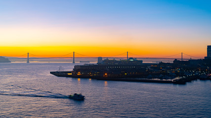 Fototapeta na wymiar Cold summer morning sunrise with the iconic Oakland Bay Bridge and a Cruise Ship in port, San Francisco, California. Famous travel location landmark on the west coast.