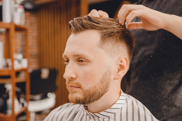 Fototapeta premium Barber master hairdresser does style with scissors and comb. Concept Barbershop