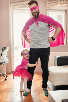 Father and daughter playing super hero and superwoman