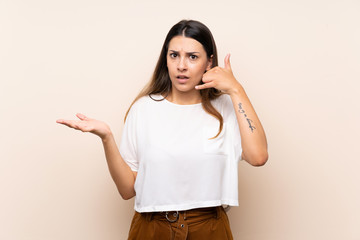 Young brunette woman over isolated background making phone gesture and doubting