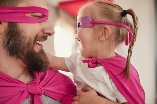 Father and daughter playing super hero and superwoman