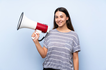 Young brunette woman over isolated blue background holding a megaphone